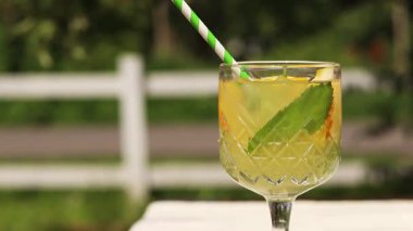 Sıcak bir yaz gününde bahçe masasında iç. Dışarıdaki ahşap bir masada kokteylli cam. Bulanık doğanın arka planına karşı bir masada limonata. Bardakta limonata ya da başka bir içecek.