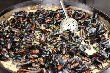 Büyük bir tavada maydanozlu ve soslu midye. Yemek katı. Sokak yemeği. Kabuklu midyeler kızartma tavasında otlarla pişiriliyor. Bir markette sosta pişirilmiş midyeler. Deniz ürünleri tabağı pişiriyorum.