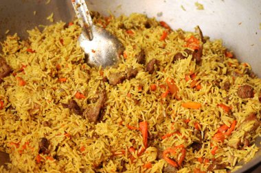 Plov bir kazanda pişirildi. Yemek katında yemek. Et, soğan, havuç ve baharatlı Plov. Lezzetli ve sıcak yemek. Adil. Açık havada yanan bir kazanda leziz bir mantar. Sokak yemekleri festivali