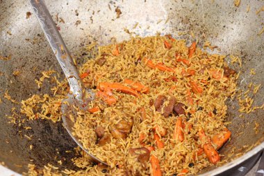 Plov bir kazanda pişirildi. Yemek katında yemek. Et, soğan, havuç ve baharatlı Plov. Lezzetli ve sıcak yemek. Adil. Açık havada yanan bir kazanda leziz bir mantar. Sokak yemekleri festivali