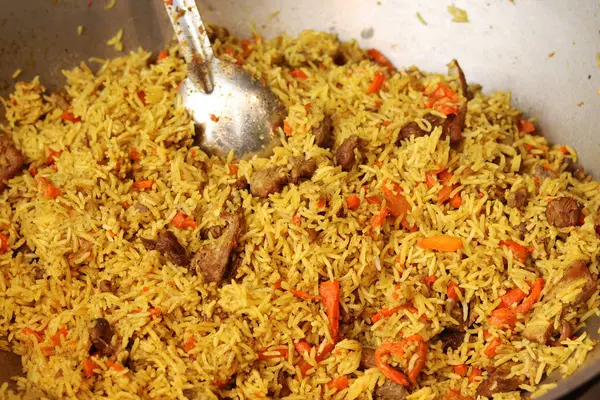 Plov bir kazanda pişirildi. Yemek katında yemek. Et, soğan, havuç ve baharatlı Plov. Lezzetli ve sıcak yemek. Adil. Açık havada yanan bir kazanda leziz bir mantar. Sokak yemekleri festivali