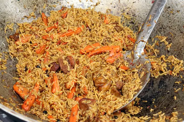 Plov bir kazanda pişirildi. Yemek katında yemek. Et, soğan, havuç ve baharatlı Plov. Lezzetli ve sıcak yemek. Adil. Açık havada yanan bir kazanda leziz bir mantar. Sokak yemekleri festivali