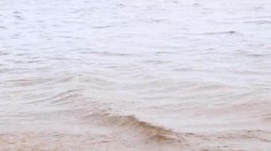 Nehir. Su yüzeyinde küçük dalgalar var. Açık hava eğlencesi. Bulutlu havada nehir, hafif rüzgar. Su akışı. Nehir yüzeyindeki dalgalar yakın plan. Doğa.