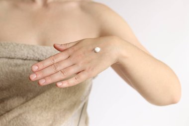 El kremi. Genç bir kadının eline nemlendirici kremle yakın çekim. Cilt bakımı. Havlu giymiş kadın el derisine krem sürüyor. Sağlıklı cilt. Kozmetoloji. Günlük rutin