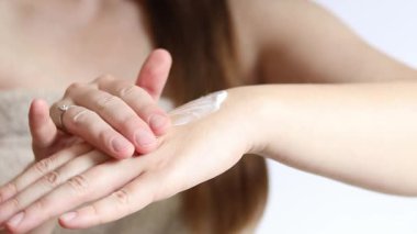 El kremi. Genç bir kadının eline nemlendirici kremle yakın çekim. Cilt bakımı. Havlu giymiş kadın el derisine krem sürüyor. Sağlıklı cilt. Kozmetoloji. Günlük rutin