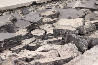 Asfalt yolda büyük parçalara ayrıldı. Şehirdeki tamirat işleri. Yol onarımı. Asfalt kaldırımlardan oluşan bir dağ. Tamir konsepti. Bir asfalt enkazı yığını. Yakın plan.
