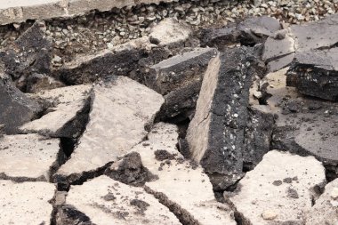 Asfalt yolda büyük parçalara ayrıldı. Şehirdeki tamirat işleri. Yol onarımı. Asfalt kaldırımlardan oluşan bir dağ. Tamir konsepti. Bir asfalt enkazı yığını. Yakın plan.