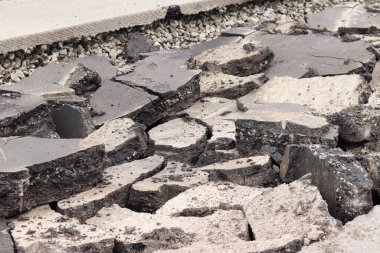 Asfalt yolda büyük parçalara ayrıldı. Şehirdeki tamirat işleri. Yol onarımı. Asfalt kaldırımlardan oluşan bir dağ. Tamir konsepti. Bir asfalt enkazı yığını. Yakın plan.