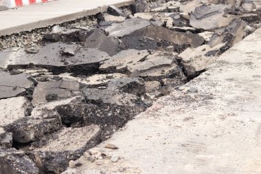 Asfalt yolda büyük parçalara ayrıldı. Şehirdeki tamirat işleri. Yol onarımı. Asfalt kaldırımlardan oluşan bir dağ. Tamir konsepti. Bir asfalt enkazı yığını. Yakın plan.