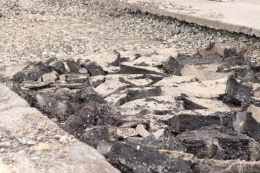 Asfalt yolda büyük parçalara ayrıldı. Şehirdeki tamirat işleri. Yol onarımı. Asfalt kaldırımlardan oluşan bir dağ. Tamir konsepti. Bir asfalt enkazı yığını. Yakın plan.