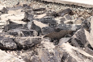 Asfalt yolda büyük parçalara ayrıldı. Şehirdeki tamirat işleri. Yol onarımı. Asfalt kaldırımlardan oluşan bir dağ. Tamir konsepti. Bir asfalt enkazı yığını. Yakın plan.