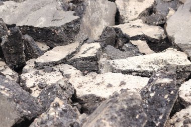 Asfalt yolda büyük parçalara ayrıldı. Şehirdeki tamirat işleri. Yol onarımı. Asfalt kaldırımlardan oluşan bir dağ. Tamir konsepti. Bir asfalt enkazı yığını. Yakın plan.
