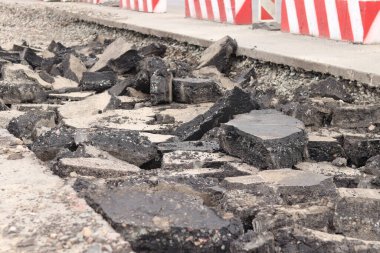 Asfalt yolda büyük parçalara ayrıldı. Şehirdeki tamirat işleri. Yol onarımı. Asfalt kaldırımlardan oluşan bir dağ. Tamir konsepti. Bir asfalt enkazı yığını. Yakın plan.