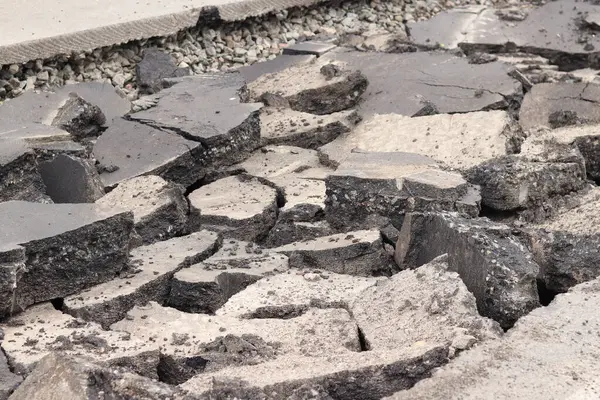 Asfalt yolda büyük parçalara ayrıldı. Şehirdeki tamirat işleri. Yol onarımı. Asfalt kaldırımlardan oluşan bir dağ. Tamir konsepti. Bir asfalt enkazı yığını. Yakın plan.