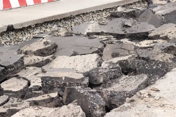 Asfalt yolda büyük parçalara ayrıldı. Şehirdeki tamirat işleri. Yol onarımı. Asfalt kaldırımlardan oluşan bir dağ. Tamir konsepti. Bir asfalt enkazı yığını. Yakın plan.