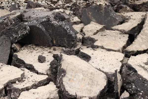 Asfalt yolda büyük parçalara ayrıldı. Şehirdeki tamirat işleri. Yol onarımı. Asfalt kaldırımlardan oluşan bir dağ. Tamir konsepti. Bir asfalt enkazı yığını. Yakın plan.