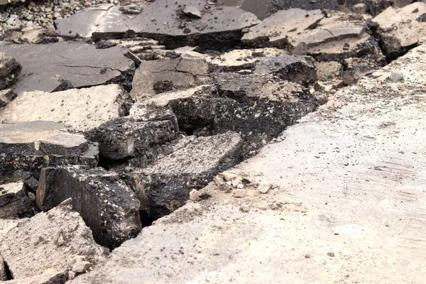 Asfalt yolda büyük parçalara ayrıldı. Şehirdeki tamirat işleri. Yol onarımı. Asfalt kaldırımlardan oluşan bir dağ. Tamir konsepti. Bir asfalt enkazı yığını. Yakın plan.