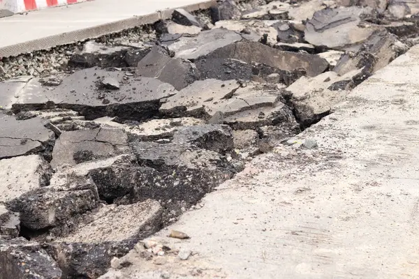 Asfalt yolda büyük parçalara ayrıldı. Şehirdeki tamirat işleri. Yol onarımı. Asfalt kaldırımlardan oluşan bir dağ. Tamir konsepti. Bir asfalt enkazı yığını. Yakın plan.