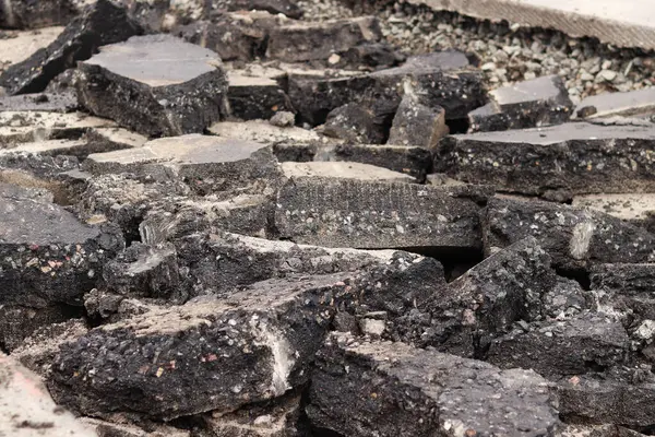 Asfalt yolda büyük parçalara ayrıldı. Şehirdeki tamirat işleri. Yol onarımı. Asfalt kaldırımlardan oluşan bir dağ. Tamir konsepti. Bir asfalt enkazı yığını. Yakın plan.