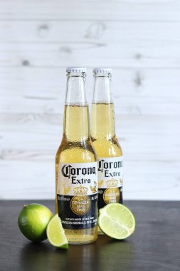 Kyiv, Ukrayna - 10 Mayıs 2025: Corona Ekstra limonlu bira, ahşap arka planda bira. Corona hafif bir bira. Limonlu şişe bira, yan görüş, boş yer. Tazeleyici içecek.