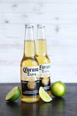Kyiv, Ukrayna - 10 Mayıs 2025: Corona Ekstra limonlu bira, ahşap arka planda bira. Corona hafif bir bira. Limonlu şişe bira, yan görüş, boş yer. Tazeleyici içecek.