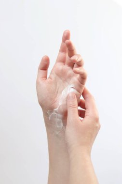 El kremi. Genç bir kadının ellerinin nemlendirici kremle yakın çekimi. Cilt bakımı. Ellerine krem süren bir kadın, hafif arka plan. Sağlıklı cilt. Kozmetoloji. Günlük rutin