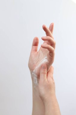 El kremi. Genç bir kadının ellerinin nemlendirici kremle yakın çekimi. Cilt bakımı. Ellerine krem süren bir kadın, hafif arka plan. Sağlıklı cilt. Kozmetoloji. Günlük rutin