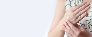 El kremi. Genç bir kadının ellerinin nemlendirici kremle yakın çekimi. Cilt bakımı. Ellerine krem süren bir kadın, hafif arka plan. Sağlıklı cilt. Kozmetoloji. Günlük rutin