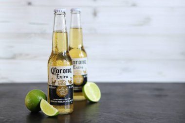 Kyiv, Ukrayna - 10 Mayıs 2025: Corona Ekstra limonlu bira, açık ahşap arka planda bira. Corona hafif bir bira. Limonlu şişe bira, yan görüş, boş yer. Tazeleyici içecek.