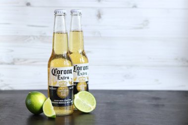 Kyiv, Ukrayna - 10 Mayıs 2025: Corona Ekstra limonlu bira, açık ahşap arka planda bira. Corona hafif bir bira. Limonlu şişe bira, yan görüş, boş yer. Tazeleyici içecek.