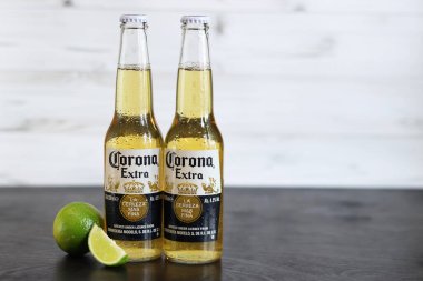 Kyiv, Ukrayna - 10 Mayıs 2025: Corona Ekstra limonlu bira, açık ahşap arka planda bira. Corona hafif bir bira. Limonlu şişe bira, yan görüş, boş yer. Tazeleyici içecek.