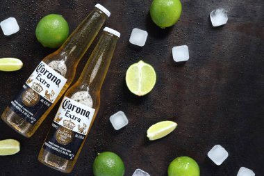 Kyiv, Ukrayna - 10 Mayıs 2025: Ahşap zemin üzerinde limon ve buz küpleri olan ekstra Corona biraları. Corona hafif bir bira. Limonlu bira, üst manzara, boş yer. Koyu bir masada bira.
