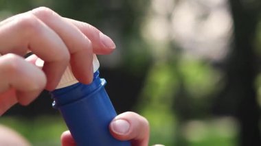 Sabun köpükleri. Parkta sabun köpüğü üflemek. Dışarıda sabun köpüğü şişiren bir kadın, yakın plan. Yaz tatili konsepti, huzurlu atmosfer. Tanınmayan kişi sabun köpüğü üflüyor.