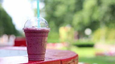 Dondurmalı meyveli milkshake. Tek kullanımlık plastik bardakta samanla yaz içkisi. Dondurma ve böğürtlen şurubuyla kahve. Yaz günü parkta serinletici bir içki.