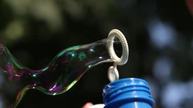 Parkta sabun köpüğü üflemek. Açık havada sabun köpüğü üfleme, yakın plan. Yaz tatili konsepti, huzurlu atmosfer. Tanınmayan kişi sabun köpüğü üflüyor. Açık hava eğlencesi. Boş zaman