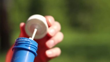 Parkta sabun köpüğü üflemek. Açık havada sabun köpüğü üfleme, yakın plan. Yaz tatili konsepti, huzurlu atmosfer. Tanınmayan kişi sabun köpüğü üflüyor. Açık hava eğlencesi. Boş zaman