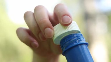 Parkta sabun köpüğü üflemek. Açık havada sabun köpüğü üfleme, yakın plan. Yaz tatili konsepti, huzurlu atmosfer. Tanınmayan kişi sabun köpüğü üflüyor. Açık hava eğlencesi. Boş zaman