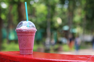 Dondurmalı meyveli milkshake. Tek kullanımlık plastik bardakta samanla yaz içkisi. Dondurma ve böğürtlen şurubuyla kahve. Yaz günü parkta serinletici bir içki.