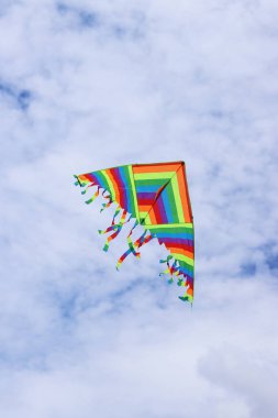 Bulutlu gökyüzüne karşı parlak uçurtma. Çocuklar ve yetişkinler için oyuncak. Açık hava aktiviteleri. Gökyüzünde renkli uçurtma uçar, rüzgarlı bir havada. Bulutsuz bir ruh hali. Uç! Parlak renkli uçurtma havada uçuşuyor.