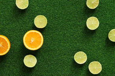 Çim arka planda portakal ve kireç yarımları, üst manzara. Yaz dönemi. Portakallar ve limonlar yapay çimlerin üzerinde. Turunçgil meyvesi. Yaz kompozisyonu. C vitamini içeren ürünler. Parlak meyve arkaplanı.
