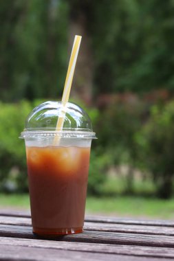 Karışık kahve. Tek kullanımlık plastik bardakta meyve suyu ve pipetli kahve. Portakal suyu, şurup ve buzlu kahve. İçkileri tazeleyip, yayalar için sıcak havada dinlenmek. Hazır içecek, yakın plan.