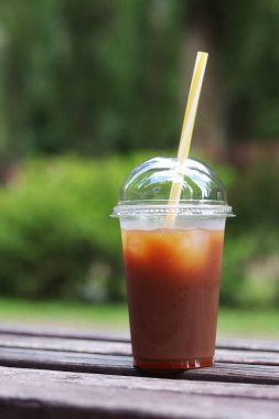 Karışık kahve. Tek kullanımlık plastik bardakta meyve suyu ve pipetli kahve. Portakal suyu, şurup ve buzlu kahve. İçkileri tazeleyip, yayalar için sıcak havada dinlenmek. Hazır içecek, yakın plan.