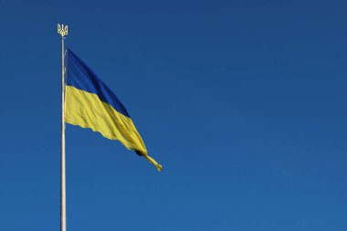 Kyiv, Ukrayna - 26 Haziran 2025: Ukrayna bayrağı ve arması gökyüzüne karşı. Bayrak direğindeki mavi ve sarı bayrak. Ukrayna bayrağı sallıyor ve açık mavi gökyüzü. Ulusal kimlik