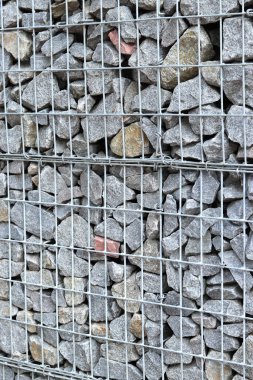 Galvanize ağ içinde harabe taşı. Geçmişi. Duvarları örmek için taşlardan örülmüş Gabion şiltesi. Ağlı taşlar, dekoratif duvarlar, güçlendirme