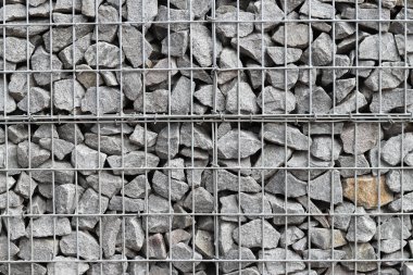 Galvanize ağ içinde harabe taşı. Geçmişi. Duvarları örmek için taşlardan örülmüş Gabion şiltesi. Ağlı taşlar, dekoratif duvarlar, güçlendirme