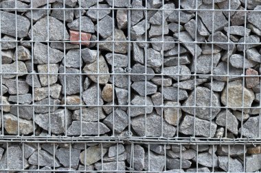 Galvanize ağ içinde harabe taşı. Geçmişi. Duvarları örmek için taşlardan örülmüş Gabion şiltesi. Ağlı taşlar, dekoratif duvarlar, güçlendirme