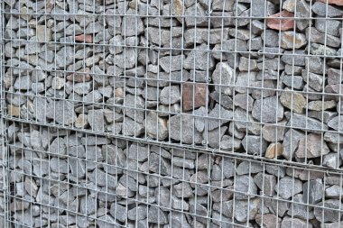 Galvanize ağ içinde harabe taşı. Geçmişi. Duvarları örmek için taşlardan örülmüş Gabion şiltesi. Ağlı taşlar, dekoratif duvarlar, güçlendirme