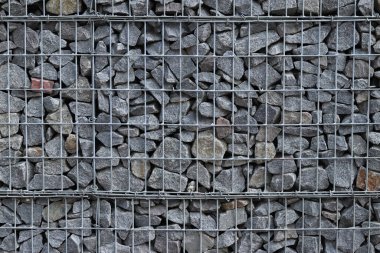 Galvanize ağ içinde harabe taşı. Geçmişi. Duvarları örmek için taşlardan örülmüş Gabion şiltesi. Ağlı taşlar, dekoratif duvarlar, güçlendirme