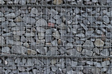 Galvanize ağ içinde harabe taşı. Geçmişi. Duvarları örmek için taşlardan örülmüş Gabion şiltesi. Ağlı taşlar, dekoratif duvarlar, güçlendirme