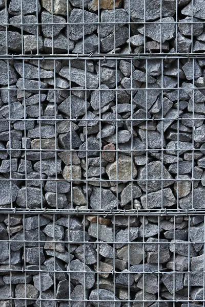 Galvanize ağ içinde harabe taşı. Geçmişi. Duvarları örmek için taşlardan örülmüş Gabion şiltesi. Ağlı taşlar, dekoratif duvarlar, güçlendirme